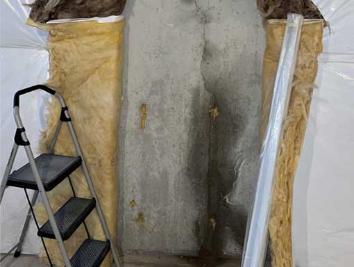 Basement-Wall-Crack-Water-Leak Vertical crack in a basement concrete wall showing damp concrete around the crack.
